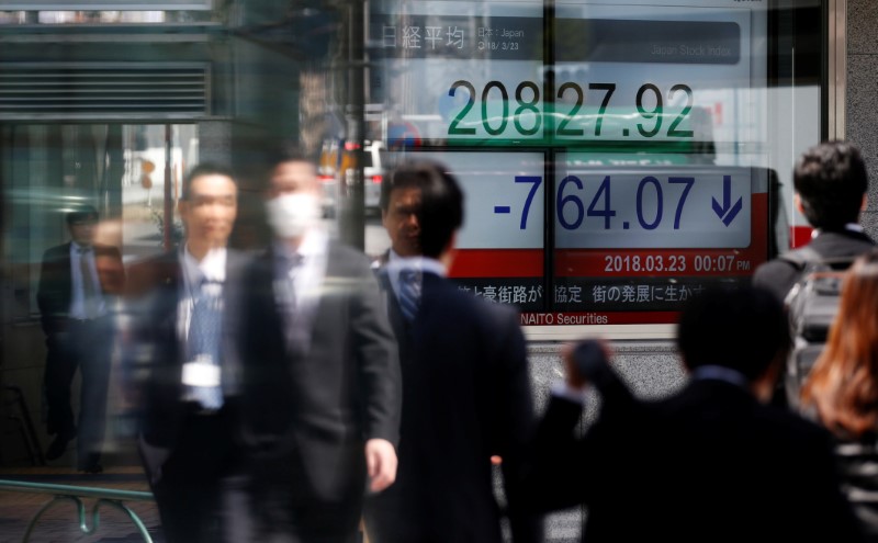 People walk past an electronic board showing Japan's Nikkei average outside a brokerage in Tokyo