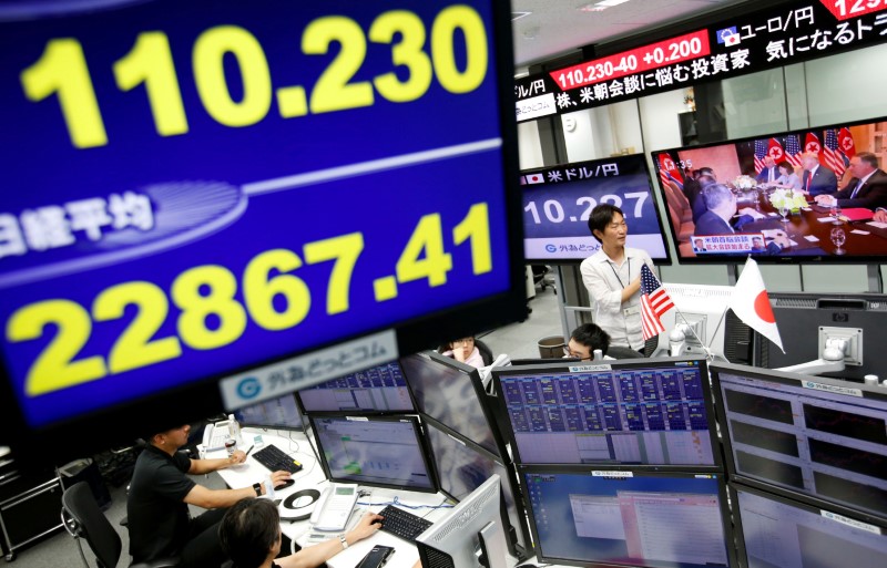 FILE PHOTO: Employees of a foreign exchange trading company work near monitors broadcasting TV news reporting from the summit between the U.S. and North Korea in Tokyo