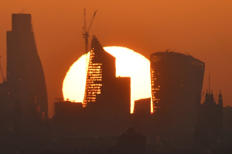 FILE PHOTO: The sun is seen rising over skyscrapers in the City of London financial district in London