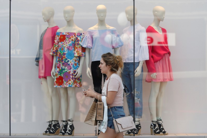 FILE PHOTO: A woman carries shopping bags while walking past a window display outside a retail store in Ottawa