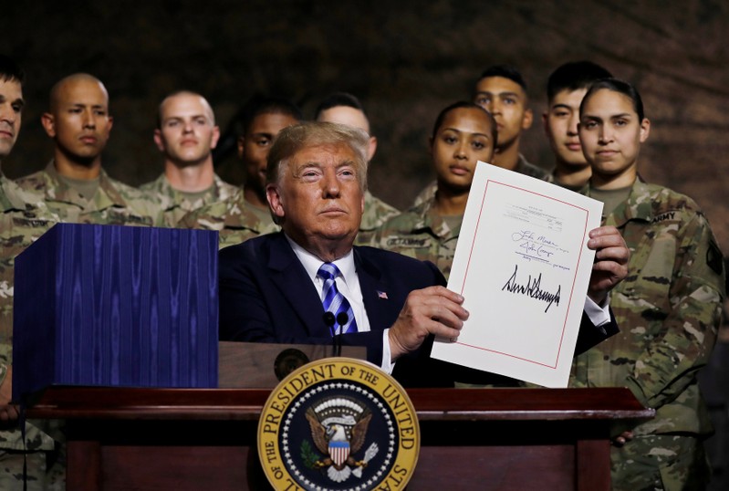 U.S. President Trump holds up the National Defense Authorization Act after signing it in front of soldiers at Fort Drum, New York