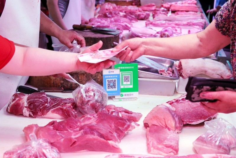 Customer pays cash at a pork stall inside a market in Nantong
