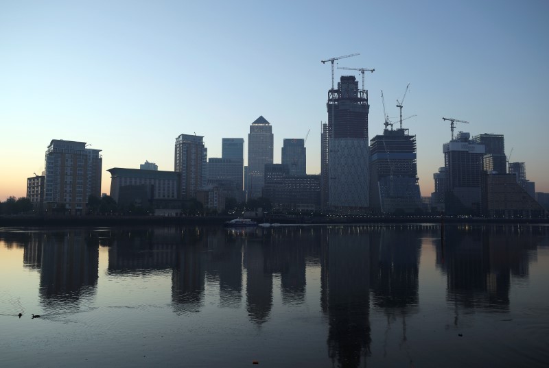 FILE PHOTO: The Canary Wharf financial district is reflected in the river Thames on a sunny morning in London