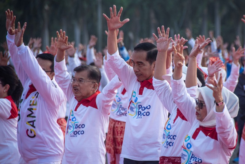 Indonesia President Joko Widodo stands beside Vice President Yusuf Kalla during a dance called 'poco-poco' at the National Monument in Jakarta