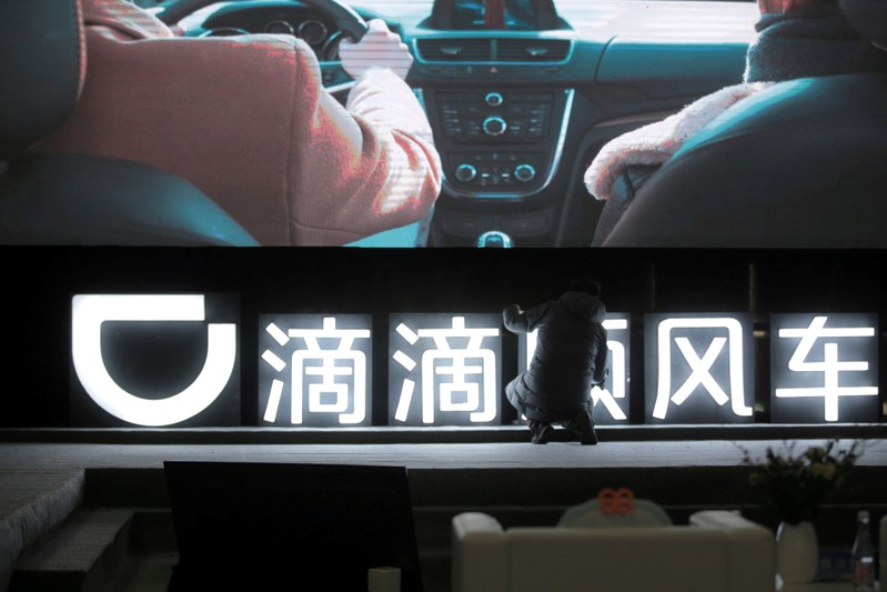 FILE PHOTO: Man is seen in front of a Didi sign before a promotional event of its Hitch service for the Spring festival travel rush, in Beijing