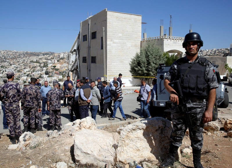 Security forces gather near a damaged building at the city of Salt