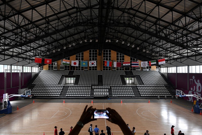 An official takes a picture inside the Basketball Hall, inside the Gelora Bung Karno sports complex, ahead of the 2018 Asian Games in Jakarta