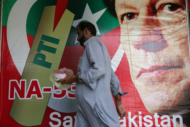 A man walks past an image of cricket star-turned-politician Imran Khan, chairman of Pakistan Tehreek-e-Insaf (PTI) at a market in Islamabad
