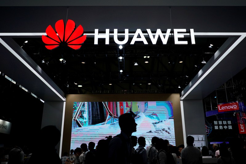 FILE PHOTO: People walk past a Huawei sign at CES (Consumer Electronics Show) Asia 2018 in Shanghai