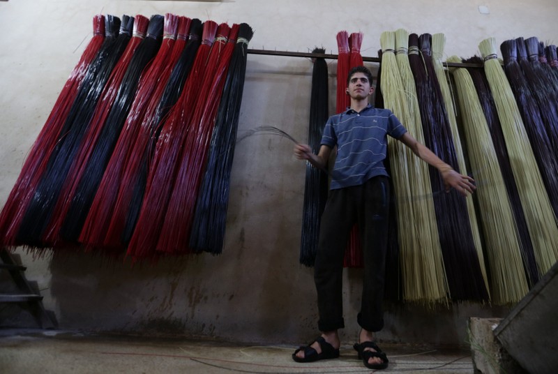 A man prepares plastic strings, used to produce mats at a factory in Idlib province
