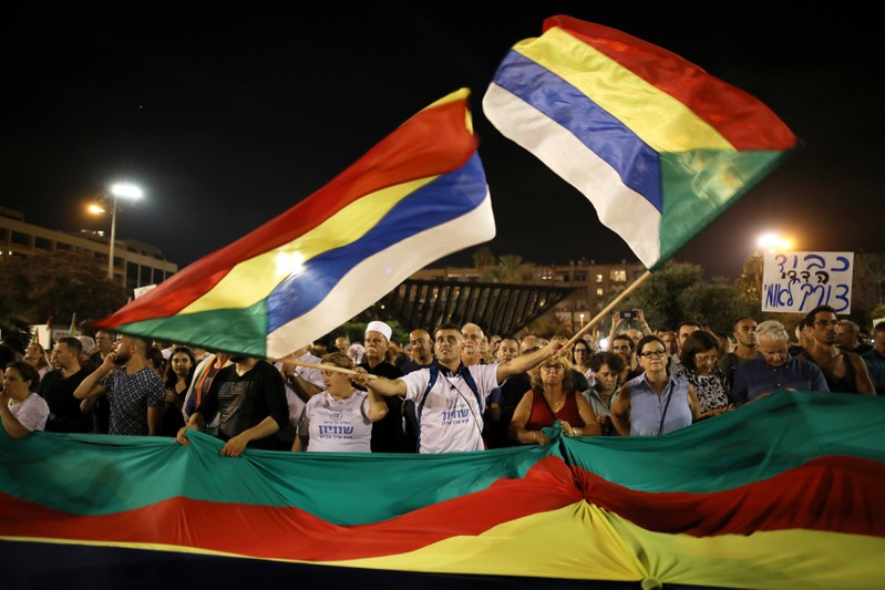A man waves Druze's flags as Israelis from the Druze minority, together with others, take part in a rally to protest against Jewish nation-state law in Rabin square in Tel Aviv