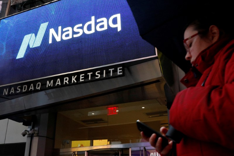 FILE PHOTO: A woman passes by the Nasdaq Market Site in Times Square in New York