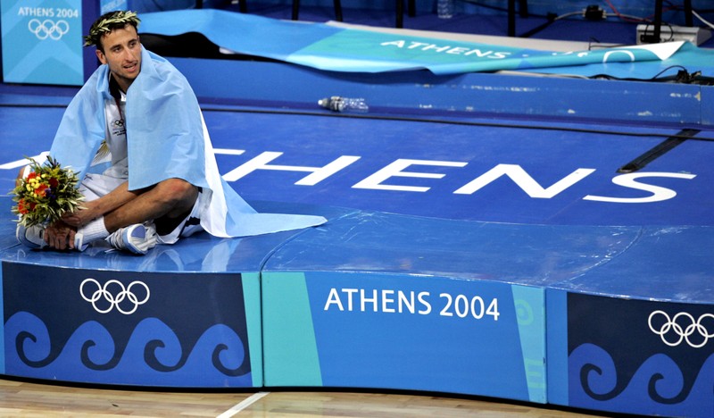 FILE PHOTO: Argentine basketball player Ginobili sits on the podium after winning the gold medal in Athens.