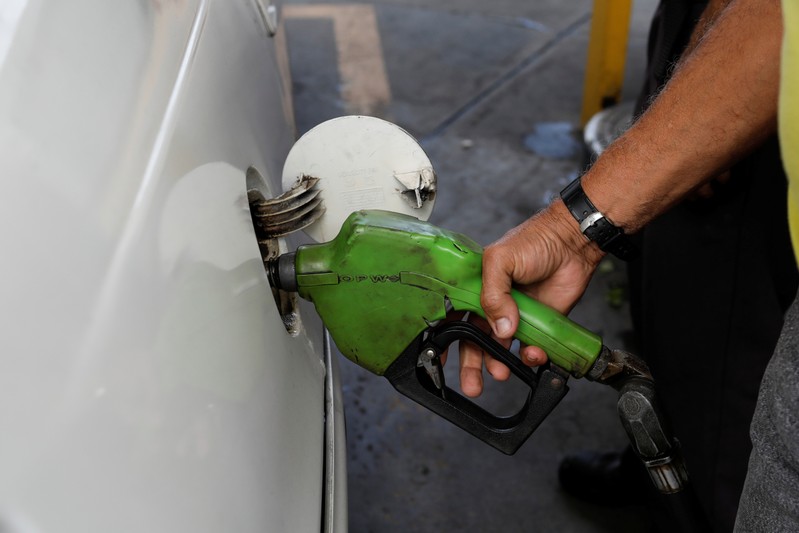 A man pumps gas into his car at a gas station in Caracas