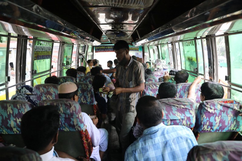 A driver's assistant collects fare from passengers of a bus in Dhaka