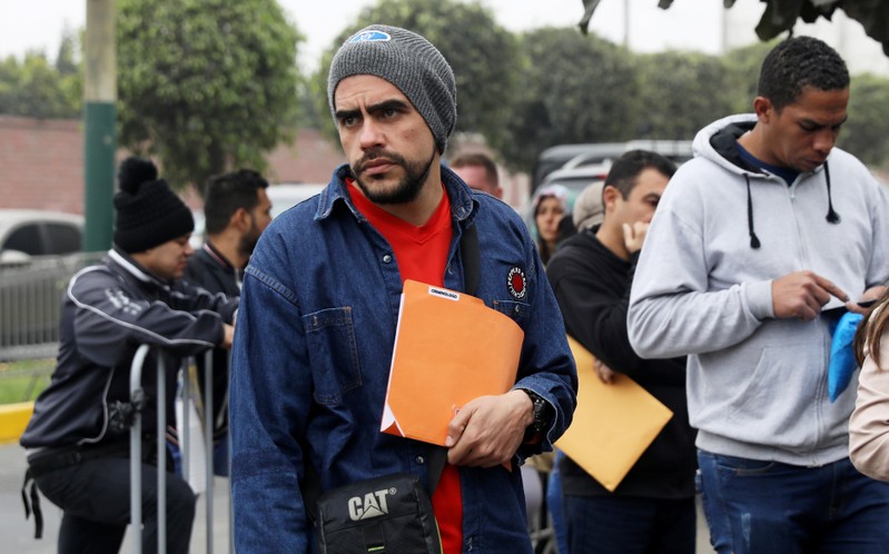 Venezuelan migrants wait at the Interpol headquarters in Lima to get paperwork needed for a temporary residency permit