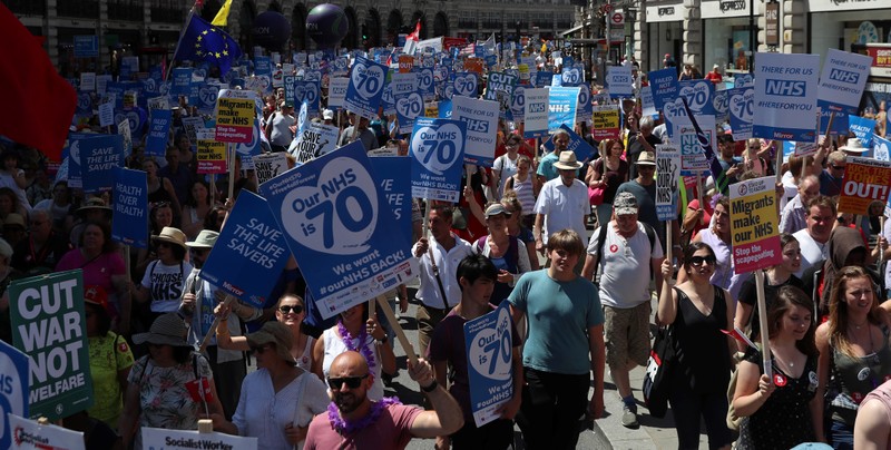 Demonstrators hold placards during a march in support of the National Health Service, in central London