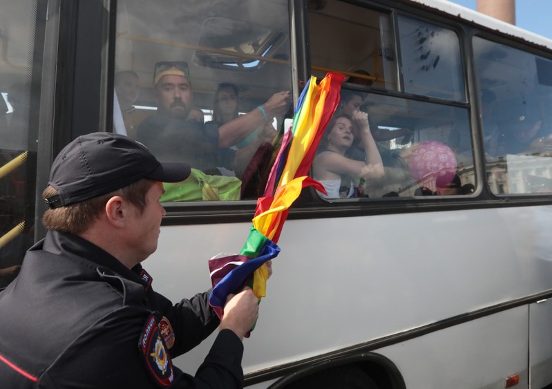 A police officer takes away a flag from detained demonstrators during the LGBT community rally in central St. Petersburg