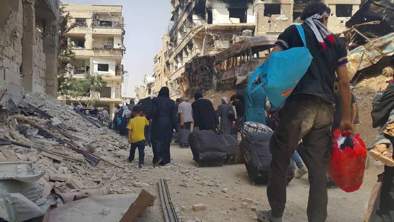 People carry their belongings before being evacuated from the besieged Damascus suburb of Daraya, after an agreement reached on Thursday between rebels and Syria's army