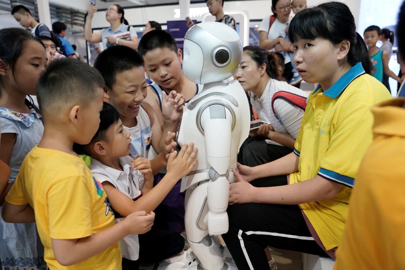 Children play with an iPal robot at Avatarmind's booth at the WRC in Beijing