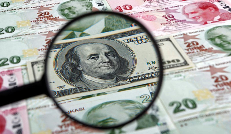 FILE PHOTO: A U.S. 100 dollar banknote is seen through a magnifying lens on top of 10 and 20 lira banknotes in Istanbul