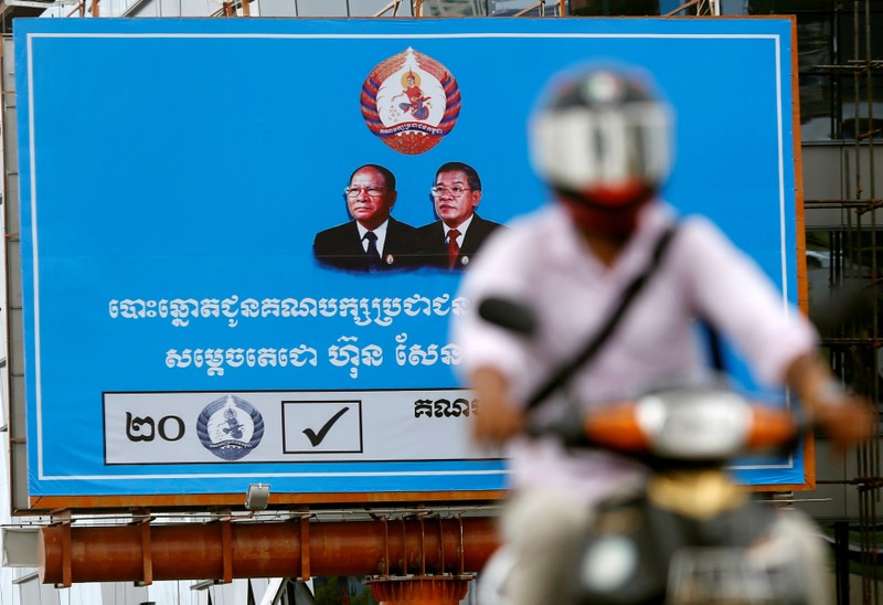 A man rides a motorcycle as a poster of the Cambodian People's Party (CPP) is seen at Koh Pich island in Phnom Penh
