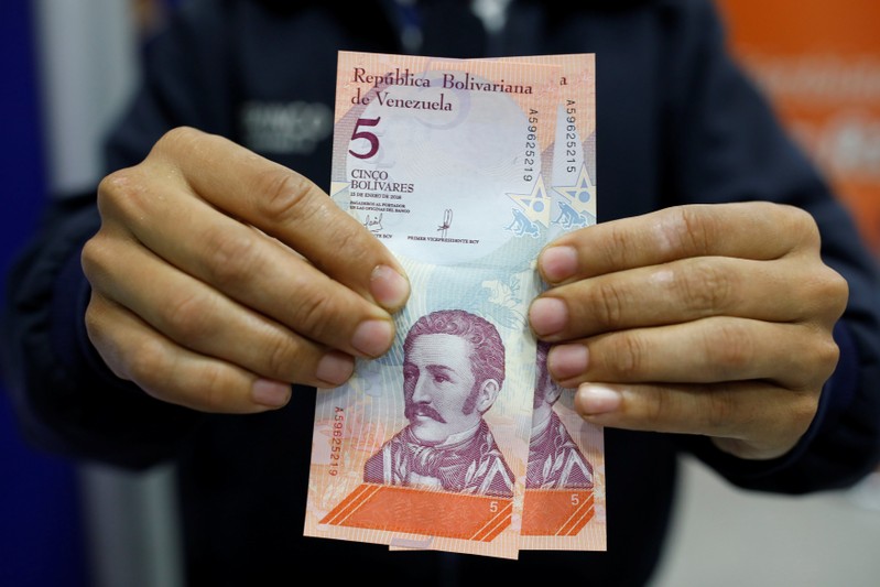 A man shows the new five Bolivar Soberano (Sovereign Bolivar) bills, after he withdrew them from an automated teller machine (ATM) at a Mercantil bank branch in Caracas