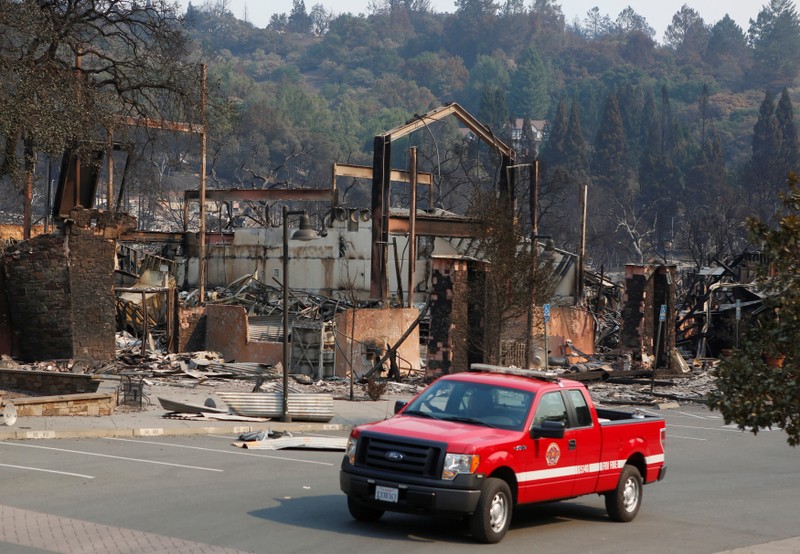 A firefighting crew drives pass a business destroyed in wildfire that tore through Santa Rosa, California
