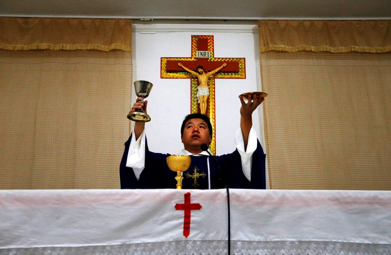 FILE PHOTO: Catholic priest Liu performs holy communion in a make-shift chapel in the village of Bai Gu Tun, located on the outskirts of the city of Tianjin, around 70 km south-east of Beijing