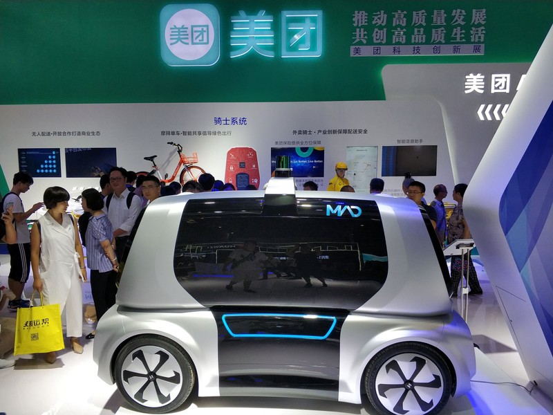 Visitors look at a Meituan Autonomous Delivery (MAD) vehicle of Chinese food delivery platform Meituan-Dianping, at the first Smart China Expo in Chongqing