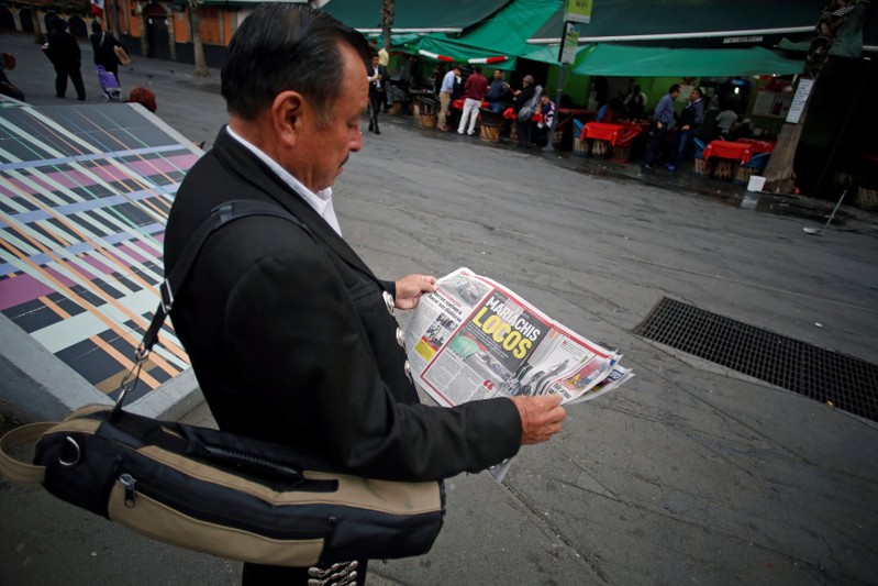 A mariachi musician reads a newspaper near a crime scene on the edge of Plaza Garibaldi in Mexico City