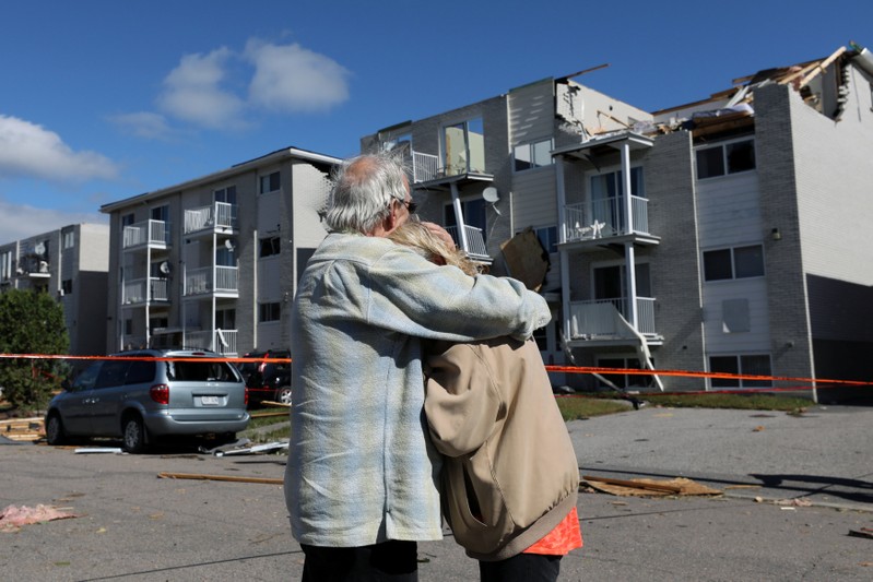 Residents embrace while looking at the damage after a tornado hit the Mont-Bleu neighbourhood in Gatineau