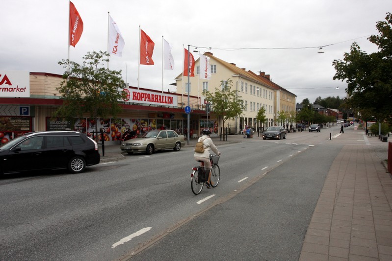 Woman rides a bike past supermarket in Kopparber