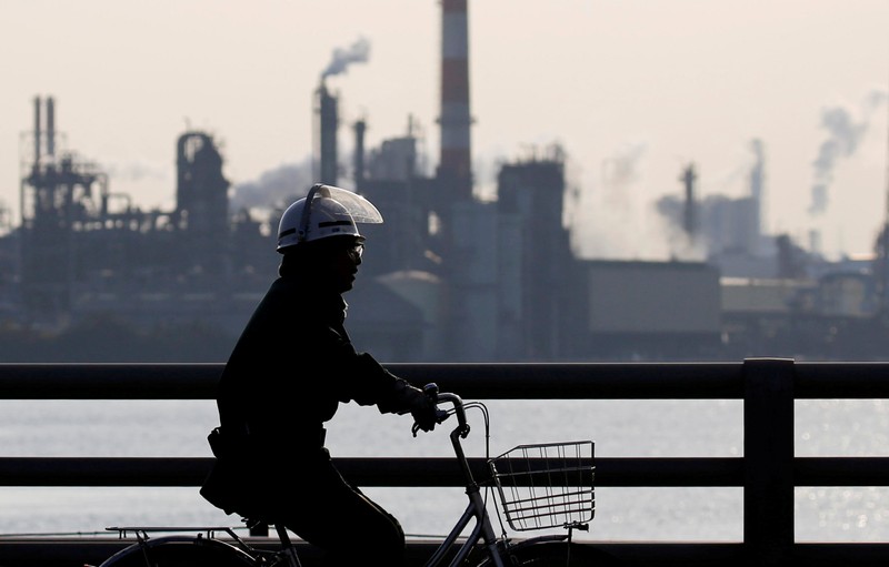 FILE PHOTO: A worker cycles near a factory at the Keihin industrial zone in Kawasaki, Japan