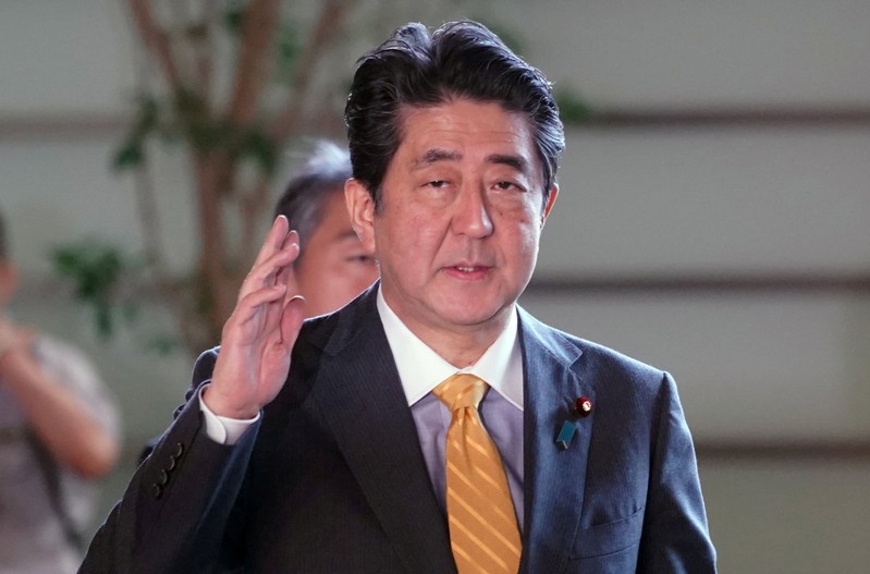 Japanese Prime Minister Shinzo Abe waves to media upon his arrival at his official residence in Tokyo
