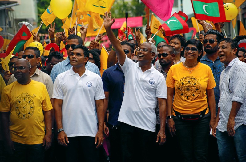 Ibrahim Mohamed Solih, Maldivian presidential candidate backed by the opposition coalition, waves as he stands next to his supporters during the final campaign rally ahead of the presidential election in Male