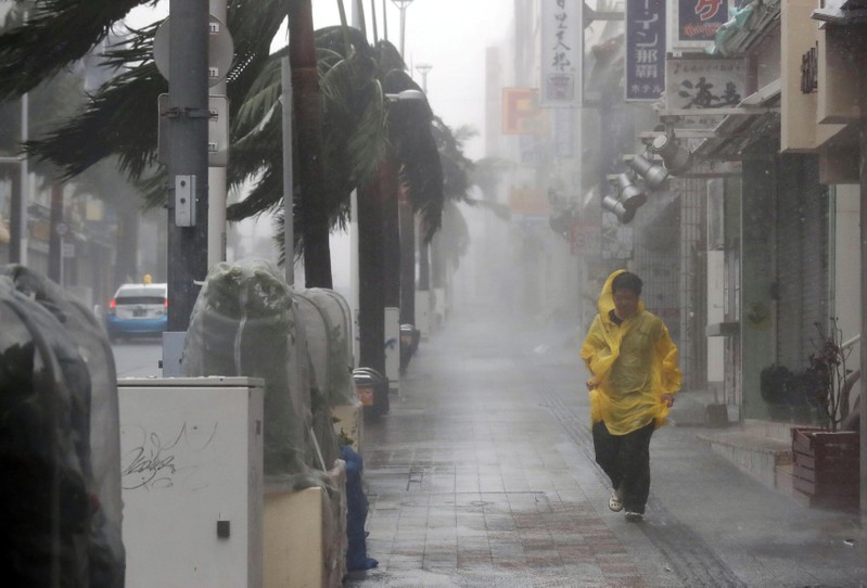 A passer-by walks in heavy rain and wind caused by Typhoon Trami in the prefectural capital Naha, on the southern island of Okinawa, in this photo taken by Kyodo