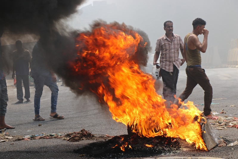 Protesters block a street with burning tires after the Yemeni Riyal has severely plunged against foreign currencies, in Aden