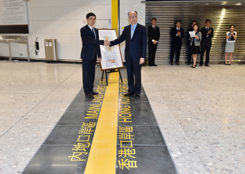 Hong Kong Secretary for Transport and Housing Frank Chan shakes hands with Deputy Secretary General of the Shenzhen Municipal People's Government Yang Xiuyou from mainland China during a handover ceremony at West Kowloon Terminus