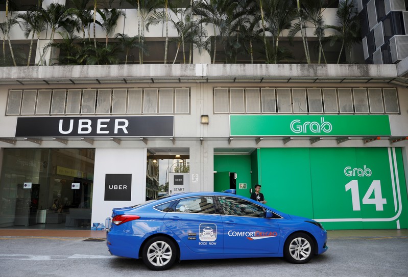 FILE PHOTO: A ComfortDelgro taxi passes Uber and Grab offices in Singapore