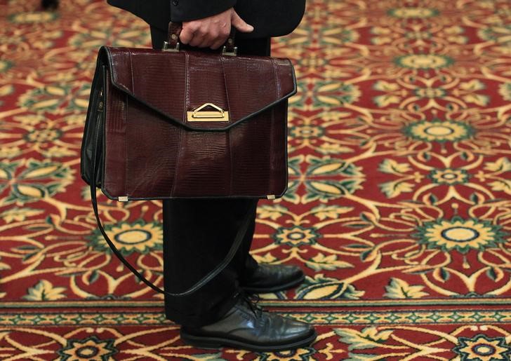 A man holds his briefcase while waiting in line during a job fair in Melville, New York