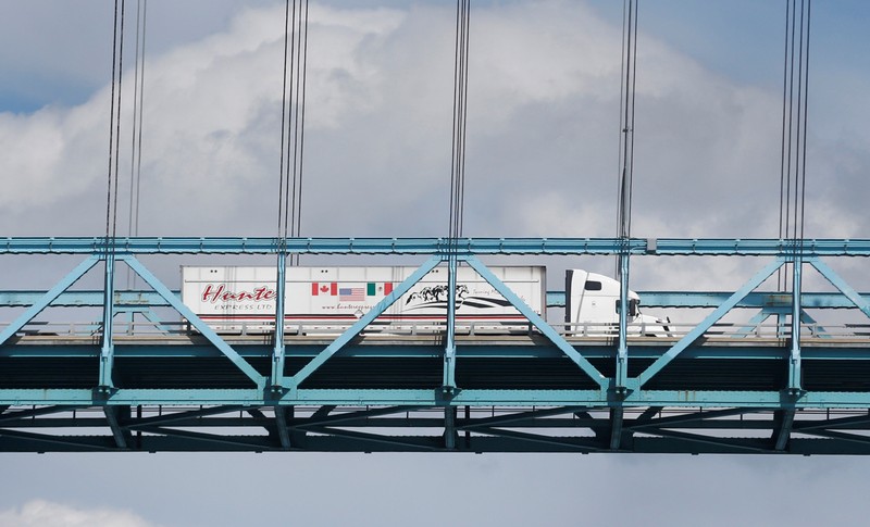 FILE PHOTO: A commercial truck with a Canada, United States and Mexico flag on its side is seen crossing over the Ambassador Bridge into Windsor, Ontario from Detroit,