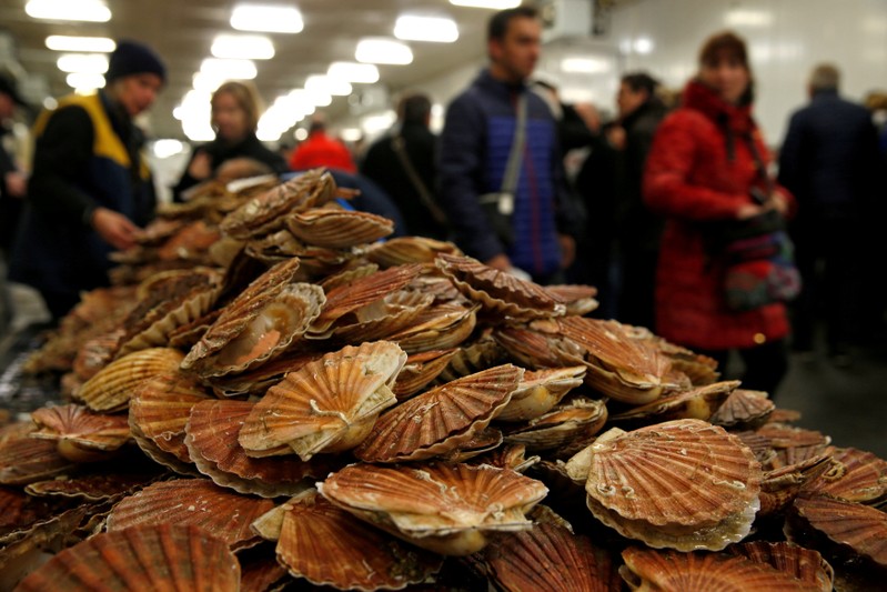 FILE PHOTO: Customers look at scallops on a market stall during an annual celebration of scallops in Port-en-Bessin