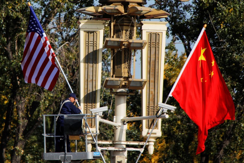 FILE PHOTO: A worker places U.S. and China flags near the Forbidden City ahead of a visit by U.S. President Donald Trump to Beijing, in Beijing