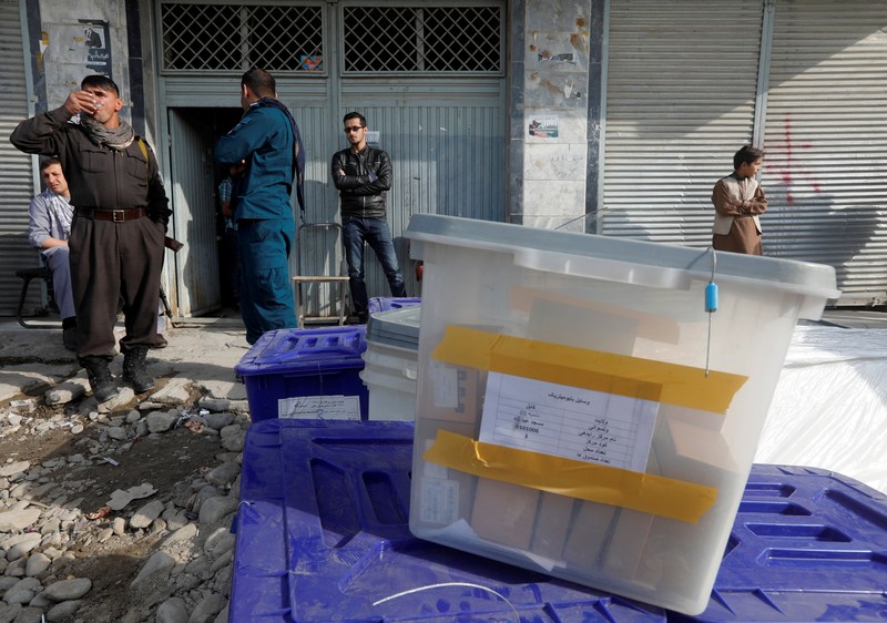Afghan police officers stand guard while election commission workers prepare ballot boxes and election material at a polling station in Kabul
