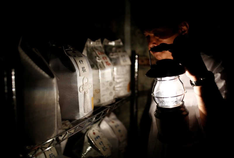 Kazuyuki Kitami, a city official of Yokosuka, holds a lantern as he visits a facility which keeps the unclaimed burial urns containing ashes of the dead in Yokosuka