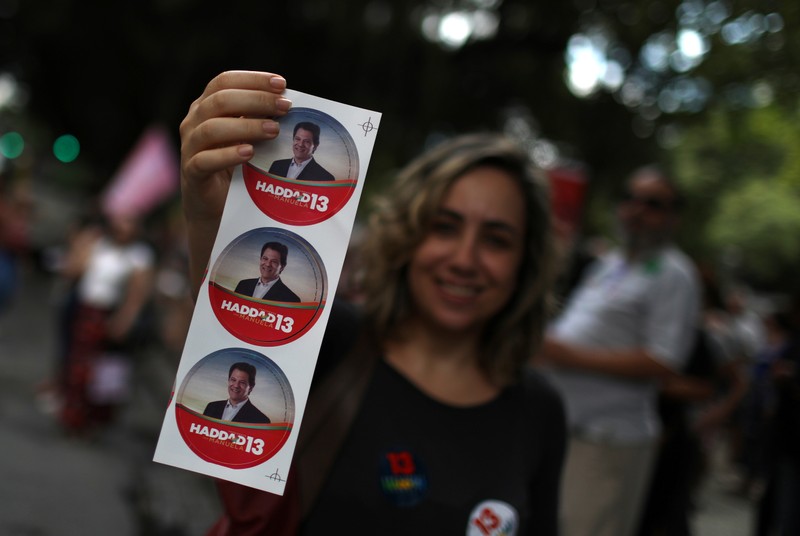 A supporter of presidential candidate Fernando Haddad holds stickers during a demonstration in Rio de Janeiro