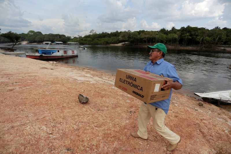 An electoral worker carries an electronic ballot box, at Nossa Senhora de Fatima community, along the Negro River