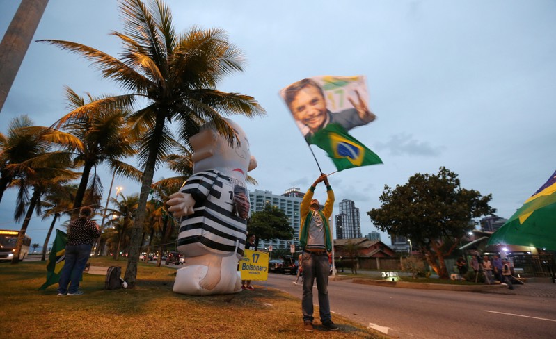A supporter of Brazilian presidential candidate Jair Bolsonaro is seen next to an inflatable doll, also known as Pixuleco, depicting former Brazilian president Luiz Inacio Lula da Silva, in front of Bolsonaro's condominium in Rio de Janeiro