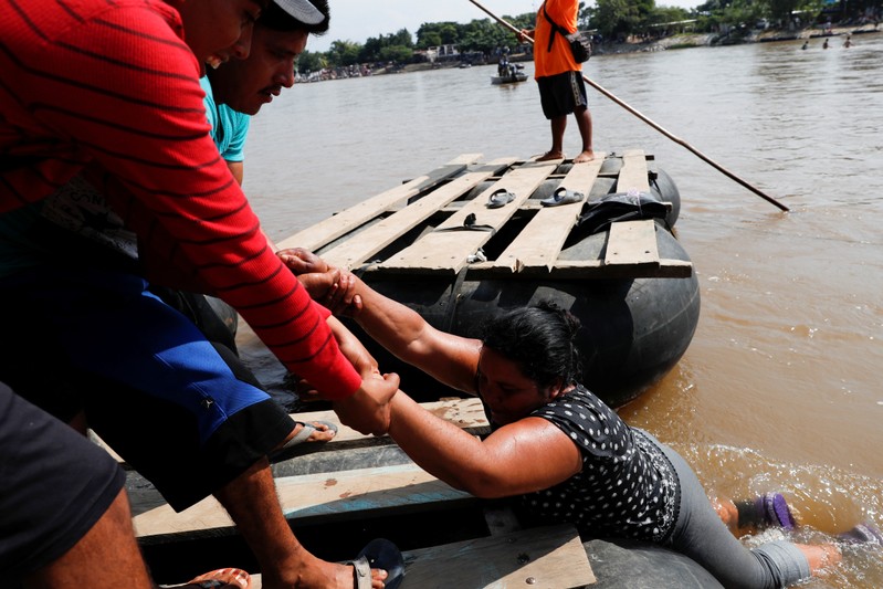Blanca Ortega, migrant from Honduras, part of a caravan trying to reach the U.S., is helped out of the water by people on makeshift rafts, as she crosses the Suchiate river to enter Mexico, in Ciudad Hidalgo